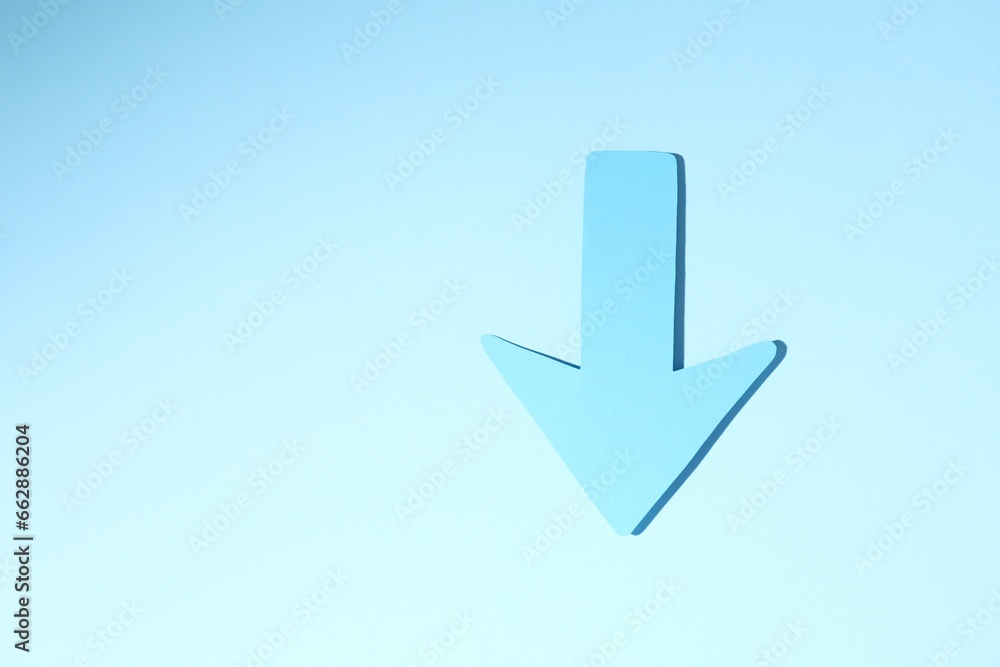 One paper arrow on light blue background, top view. Space for text One paper arrow on light blue background, top view. Space for text
