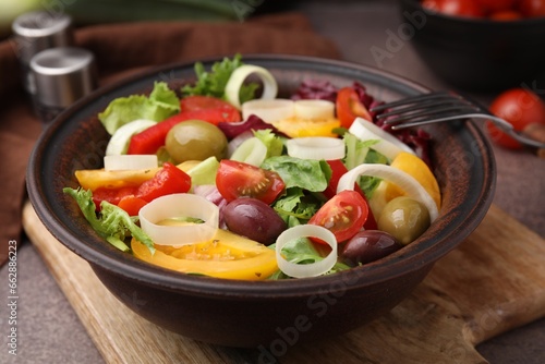 Bowl of tasty salad with leek and olives on brown table, closeup
