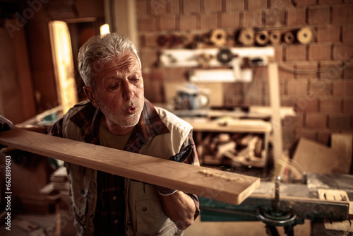 Senior male carpenter measuring wood in a carpentry shop