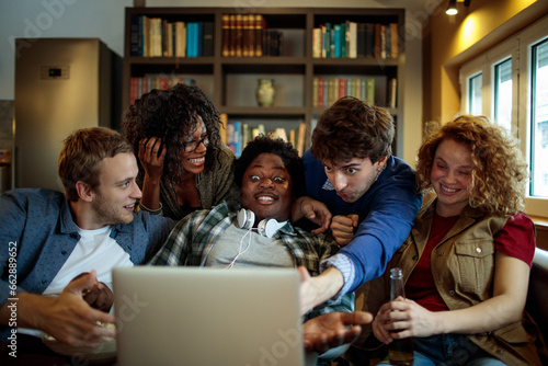 Young and diverse group of friends watching a movie together on the laptop at home