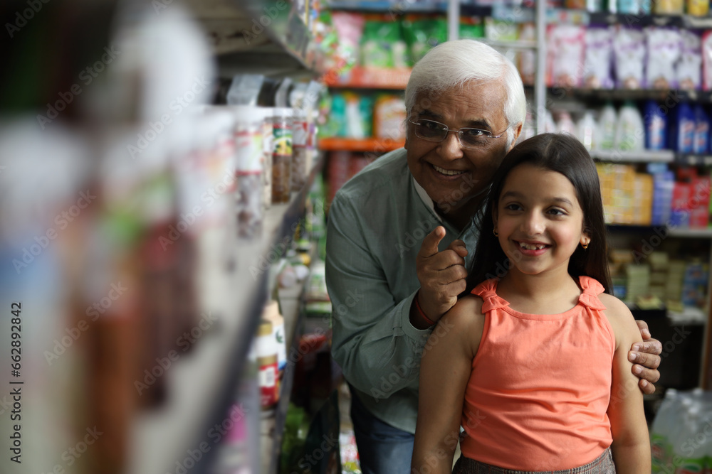 Happy Grandpa and Granddaughter enjoying purchasing in grocery store. Buying grocery for home in supermarket. Grandpa enjoying retirement with kid.
