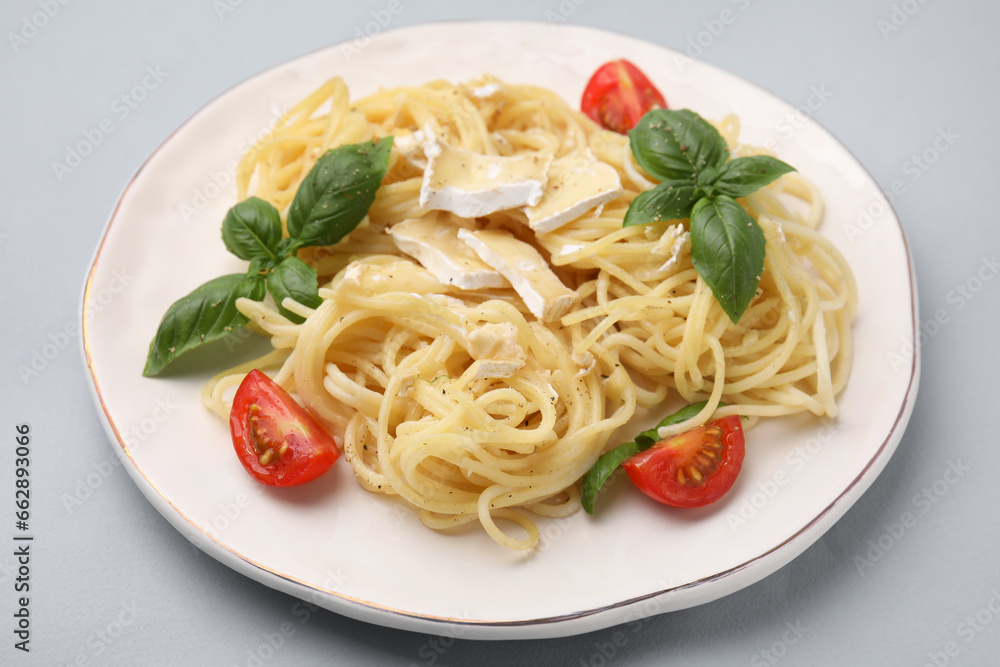 Delicious pasta with brie cheese, tomatoes and basil leaves on grey background, closeup Delicious pasta with brie cheese, tomatoes and basil leaves on grey background, closeup