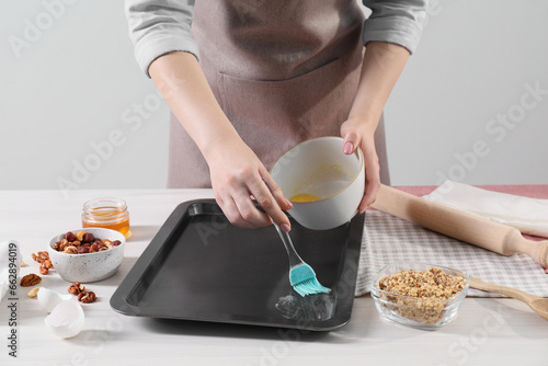 Making delicious baklava. Woman buttering baking pan at white wooden table, closeup © New Africa