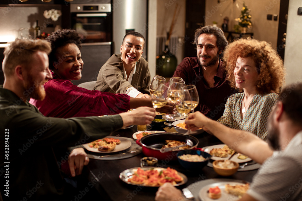 Diverse age group of friends having lunch and wine together in the kitchen at home Diverse age group of friends having lunch and wine together in the kitchen at home