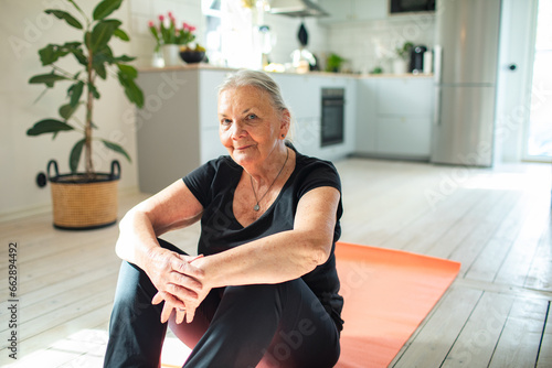 Portrait of a senior woman sitting on the living room floor at home photo
