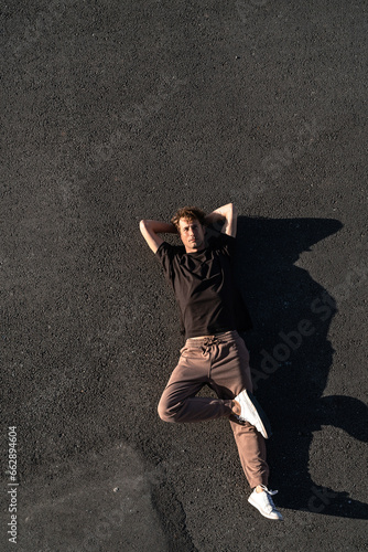 Top view of young man carefree lying on the asphalt