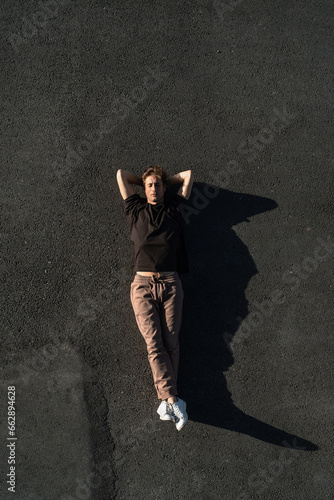 Top view of young man carefree lying on the asphalt