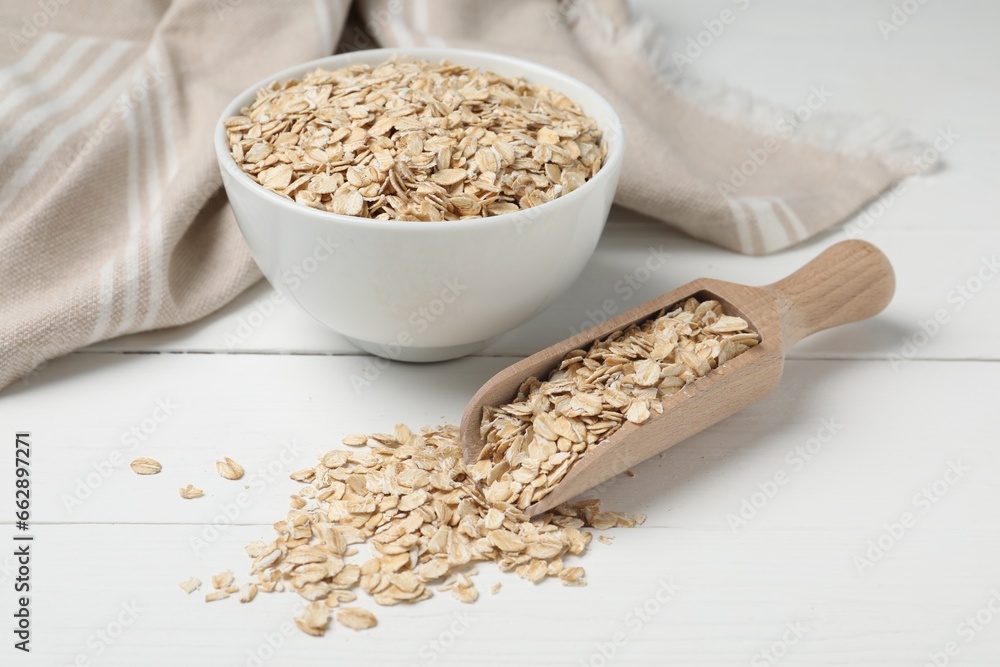 Bowl and scoop with oatmeal on white wooden table Bowl and scoop with oatmeal on white wooden table