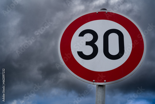 Speed sign 30 kilometers per hour with cloudy sky in the background