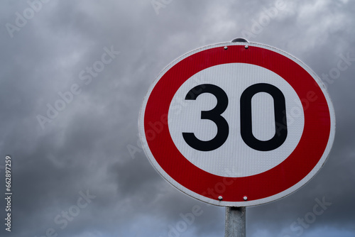 Round speed sign 30 kilometers per hour with cloudy sky in the background