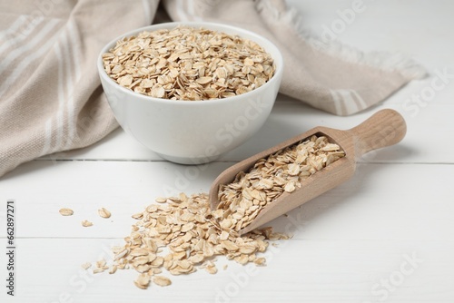Bowl and scoop with oatmeal on white wooden table