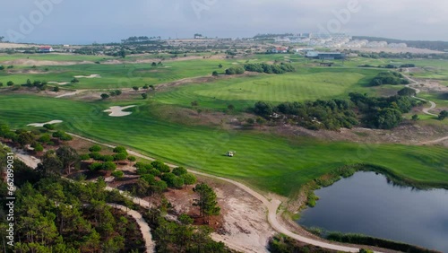 Aerial shot of golf players near hole with golfcar on private luxurious golfing field in gated community. Lush green grass field, heavy usage of water for luxury entertainment  photo