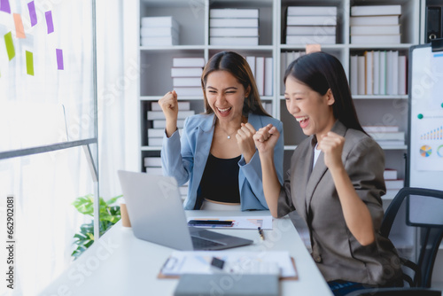 Two Asian businesswoman is excited and delighted achieved goal with laptop computer at office.