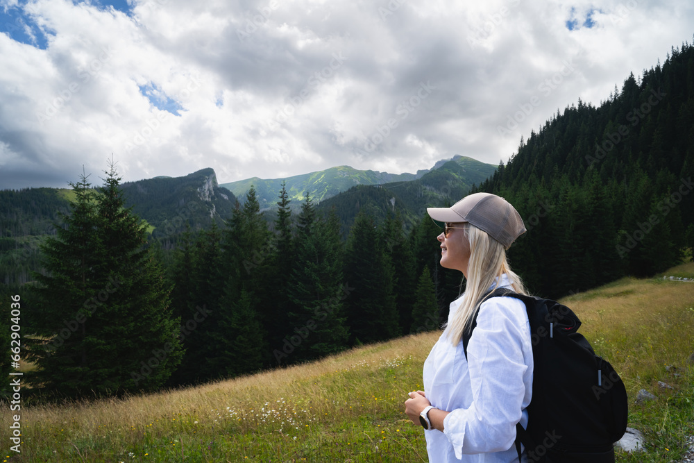 A young girl in a white linen shirt hiking in the Tatras in summer at the foot of the mountains.