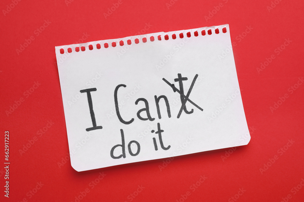 Motivation concept. Changing phrase from I Can't Do It into I Can Do It by crossing out letter T on red background, top view