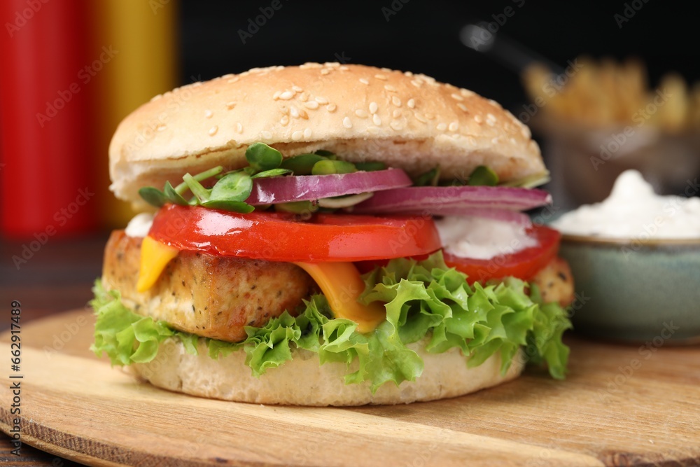 Delicious burger with tofu and fresh vegetables on wooden board, closeup Delicious burger with tofu and fresh vegetables on wooden board, closeup