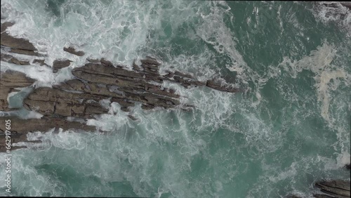 vista superior desde dron, mostrando la rompiente de las olas sobre las rocas photo