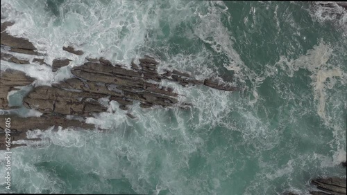 vista superior desde dron, mostrando la rompiente de las olas sobre las rocas