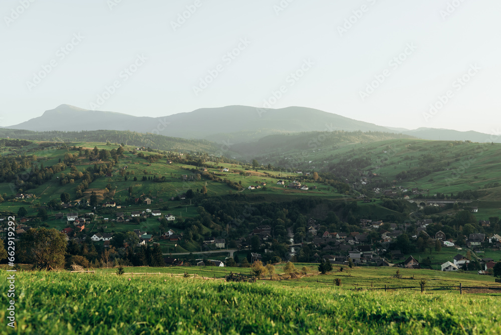 Meadow with green grass and mountains with village view Yasinya, Zakarpattia