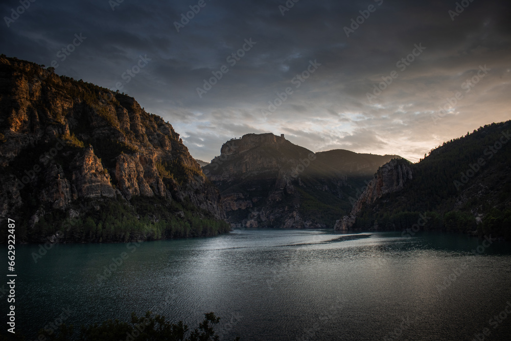 Lake between mountains with ray of sunset light in the background