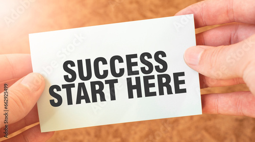 SUCCESS START HERE word inscription on white card paper sheet in hands of a businessman.