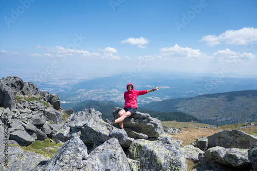 Woman sitting on a rocks in the summer mountain with stunning view 