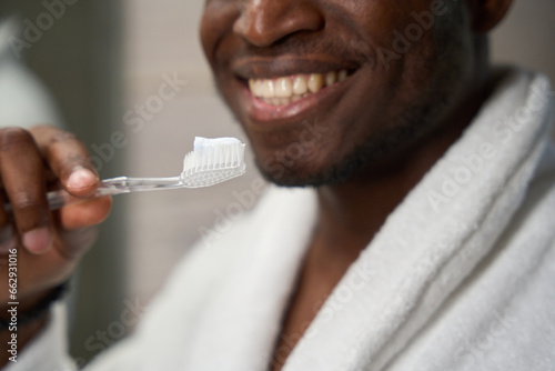 Man in a bathrobe is prepared to brush his teeth