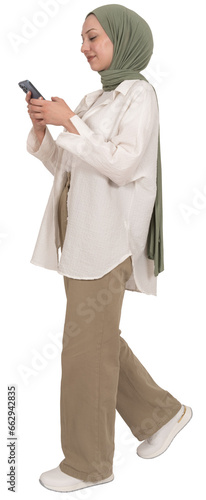 Walking using mobile phone, full length body view caucasian muslim woman in hijab walking using mobile phone. Holding smartphone technology device taking step. Messaging, browsing, social media.