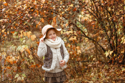 Portrait of a smiling young girl in a hat in an autumn park.