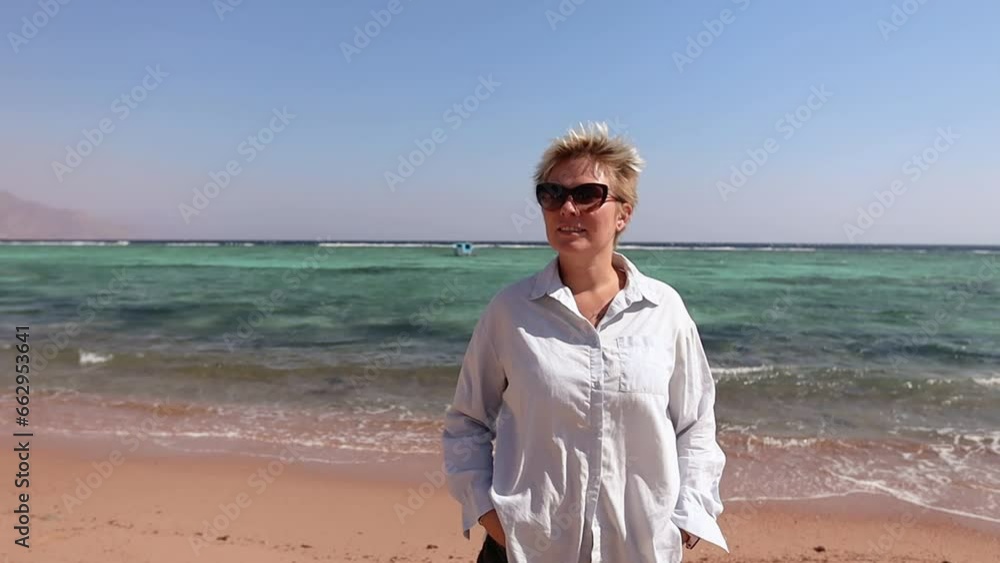 Young attractive blond woman dressed in whire shirt on the beach on sunny summer day Young attractive blond woman dressed in whire shirt on the beach on sunny summer day