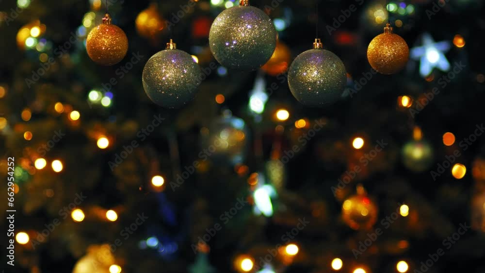 Gold and silver Christmas balls against the background of luminous garlands on a Christmas tree in blur. Medium plan Gold and silver Christmas balls against the background of luminous garlands on a Christmas tree in blur. Medium plan