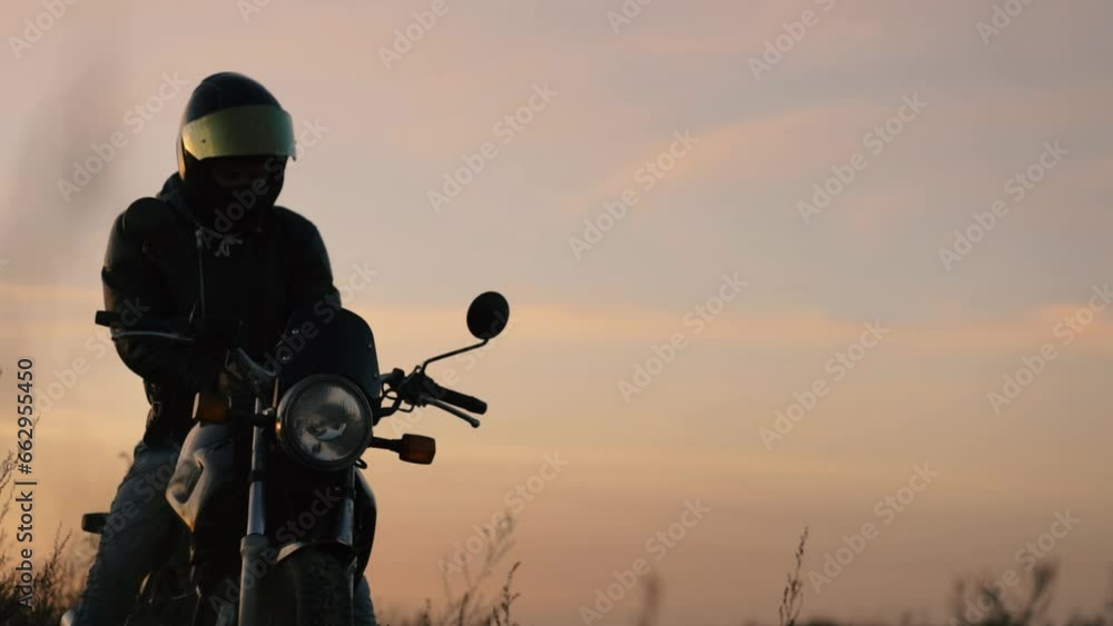 motorcyclist in a helmet and leather jacket at sunset with a classic motorcycle. Motorcycle life concept motorcyclist in a helmet and leather jacket at sunset with a classic motorcycle. Motorcycle life concept