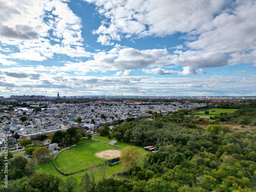 aerial view of marine park, brooklyn (baseball diamond field, neighborhood houses, distant verazzano bridge) drone photo with clouds in the sky, trees, public park in new york city