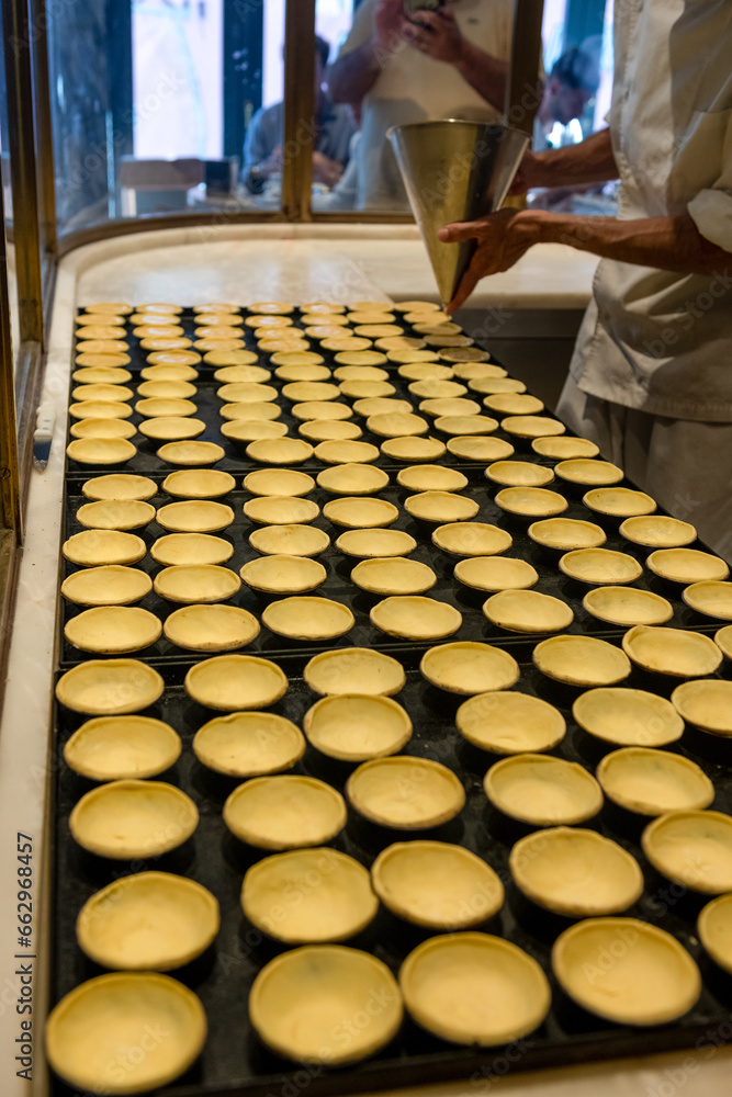 napełnianie cista kremem mlecznym w piekarni rzemieślniczej w Portugalii. Produkcja listek Pastel de nata - obrazy, fototapety, plakaty 