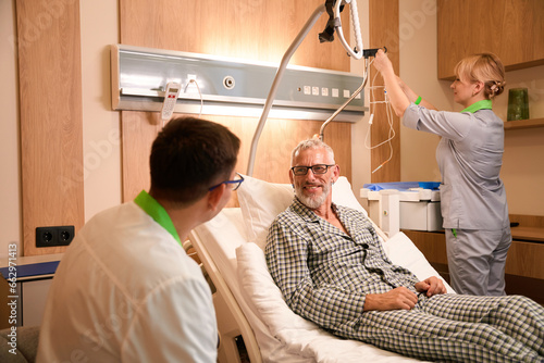 Patient in pajamas communicates with attending physician in hospital ward