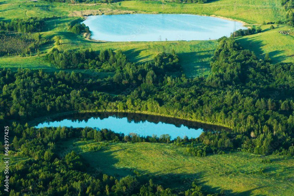 Forest lake, aerial view. View of small round lake in field near forest. Drone view of two round lakes. Location with lakes in wild. Freshwater lakes. panoramic wild landscape. Pond in rural landscape