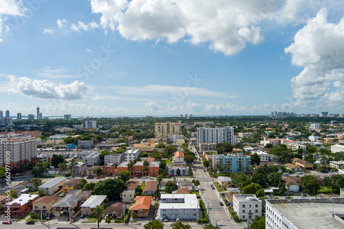 stunning aerial view with hotels, office buildings and skyscrapers in the city skyline, homes and apartments surrounded by lush green trees, cars on the street, blue sky and clouds in Miami Florida © Marcus Jones