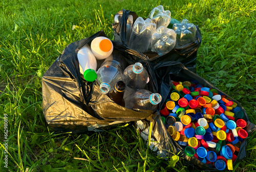 Plastic сollecting for recycling. Plastic caps and Lids plastic bottles in garbage bag for recycling. PET Water bottles and PET Bottle Caps is recyclable and Reinventing. Plastic waste collected.