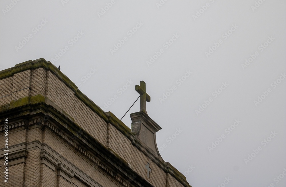 a cross on the top of a building in front of a cloudy sky a cross on the top of a building in front of a cloudy sky