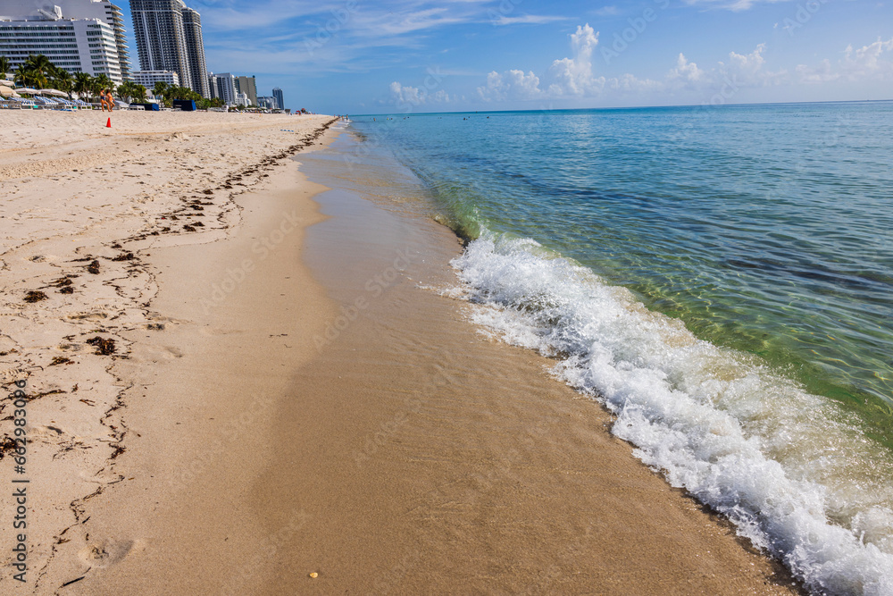 Beautiful view of waves of Atlantic Ocean rolling onto sandy beach of Miami Beach. USA.