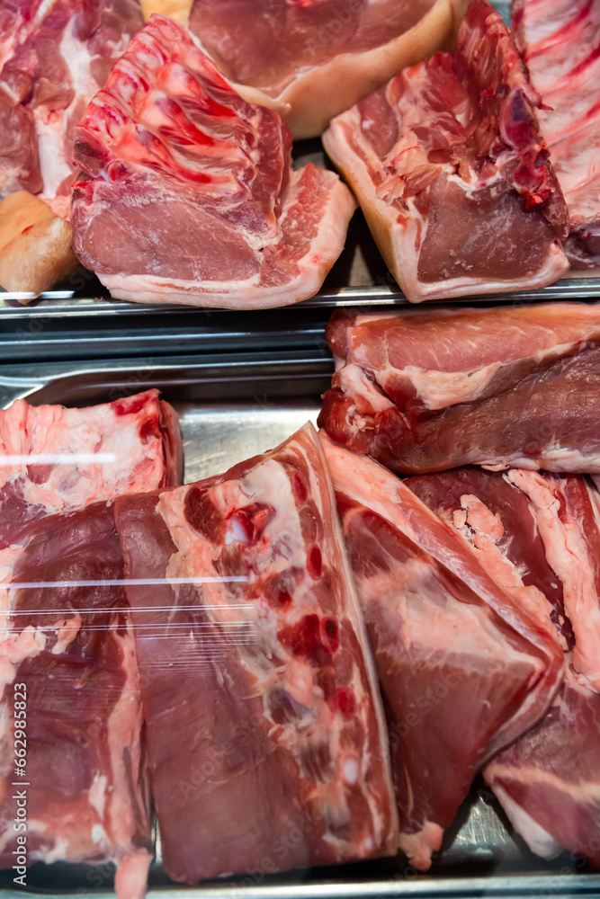 Meat showcase of supermarket with pieces of fresh pork..