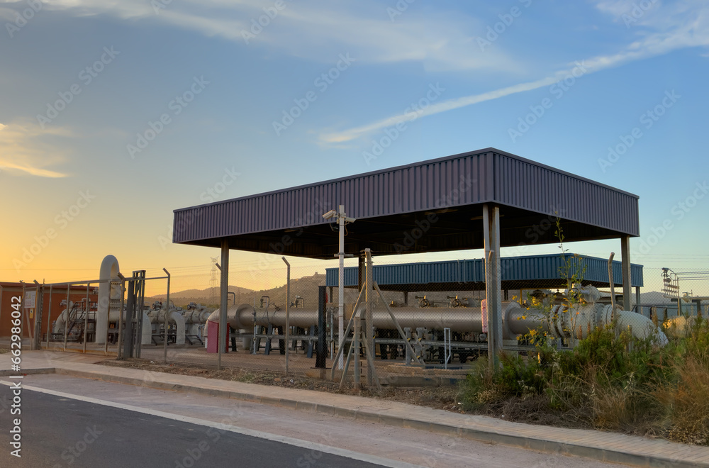 Natural gas transmission station in Spain. Spanish Gas System in Sagunto. Chemical factory. Natural gas production and Crude oil solution. Chimney smokestack emission. Gas Processing Plant on sunset. Natural gas transmission station in Spain. Spanish Gas System in Sagunto. Chemical factory. Natural gas production and Crude oil solution. Chimney smokestack emission. Gas Processing Plant on sunset.