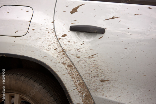 a dirty white car, splattered with mud.