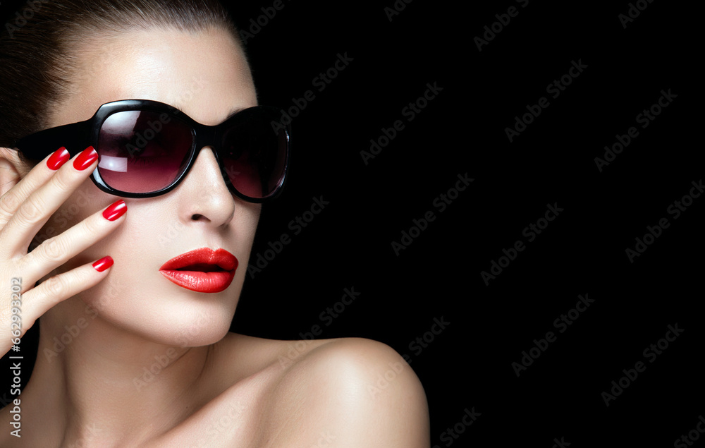 Beauty, fashion, and glamour. Elegant young woman wearing red lipstick and sunglasses in close-up portrait isolated on black background. Beauty, fashion, and glamour. Elegant young woman wearing red lipstick and sunglasses in close-up portrait isolated on black background.