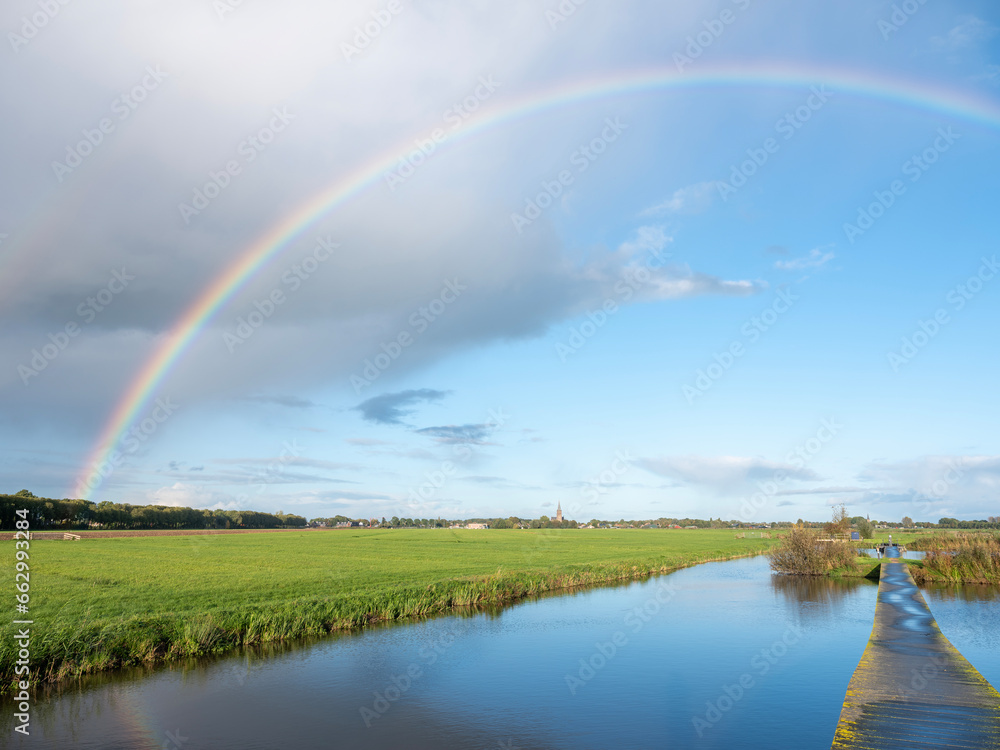 canal between dutch meadows in holland near utrecht with rainbow in blue sky canal between dutch meadows in holland near utrecht with rainbow in blue sky