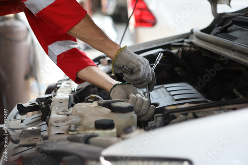 Auto mechanic working in garage. Repair service. Worker mechanics in uniform are working in auto service with lifted vehicle. Car repair maintenance. photo