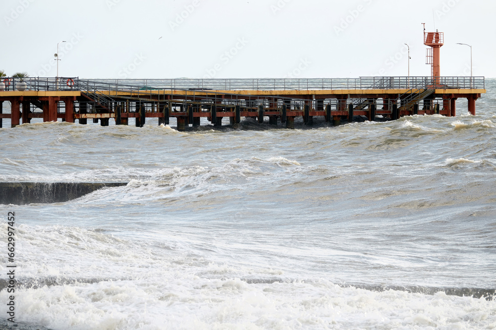 Red lighthouse on the background of the sea. Pier on the embankment. Black Sea, Adler, Russia.