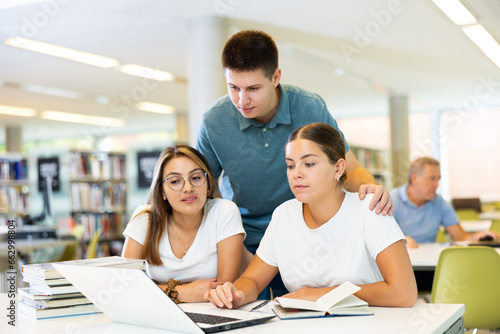 Young students collaborate study together in library with laptop