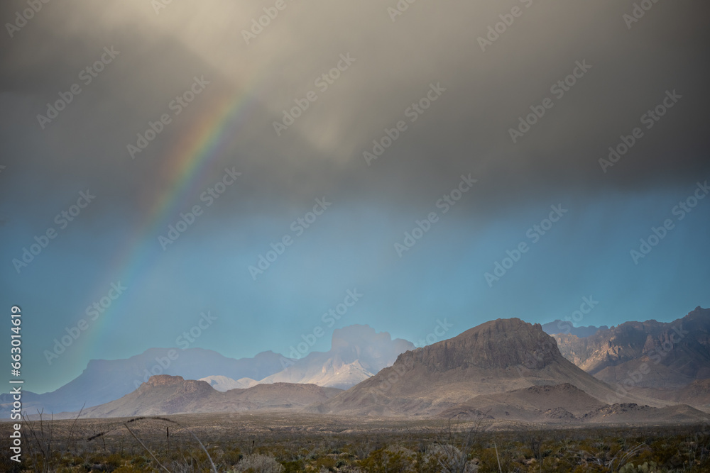 Faint Rain Falls Over The Chisos Mountains With A Rainbow Emerging To The West