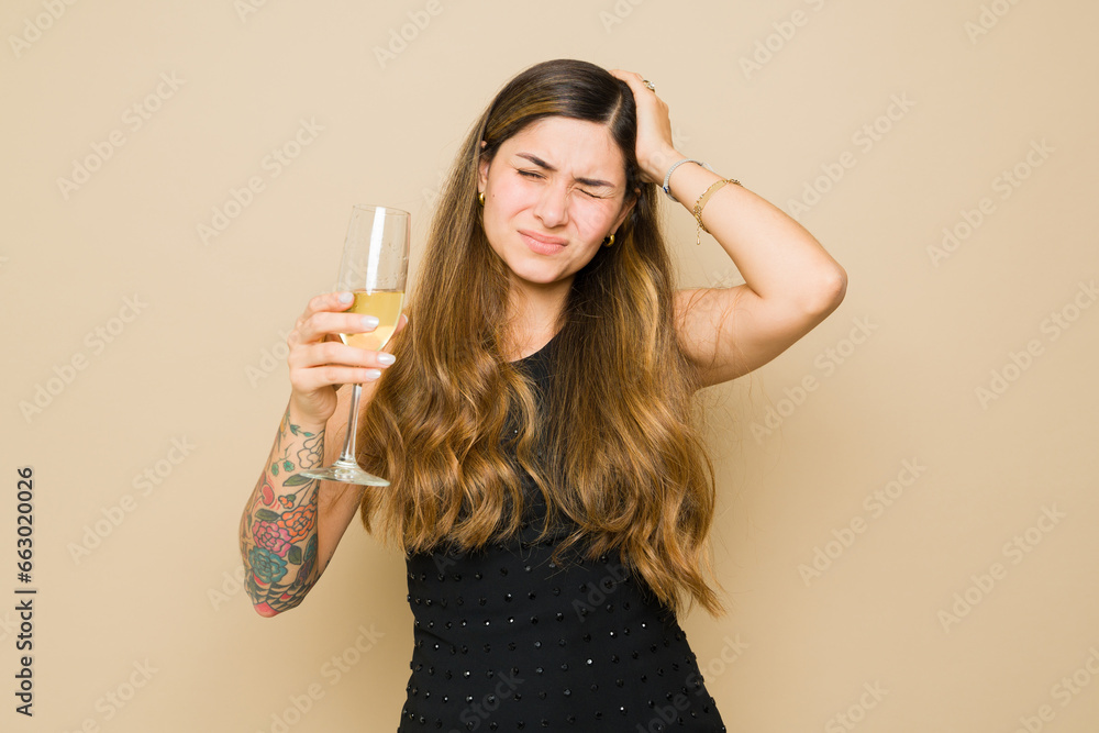Sick latin woman looking hungover drinking alcohol Sick latin woman looking hungover drinking alcohol